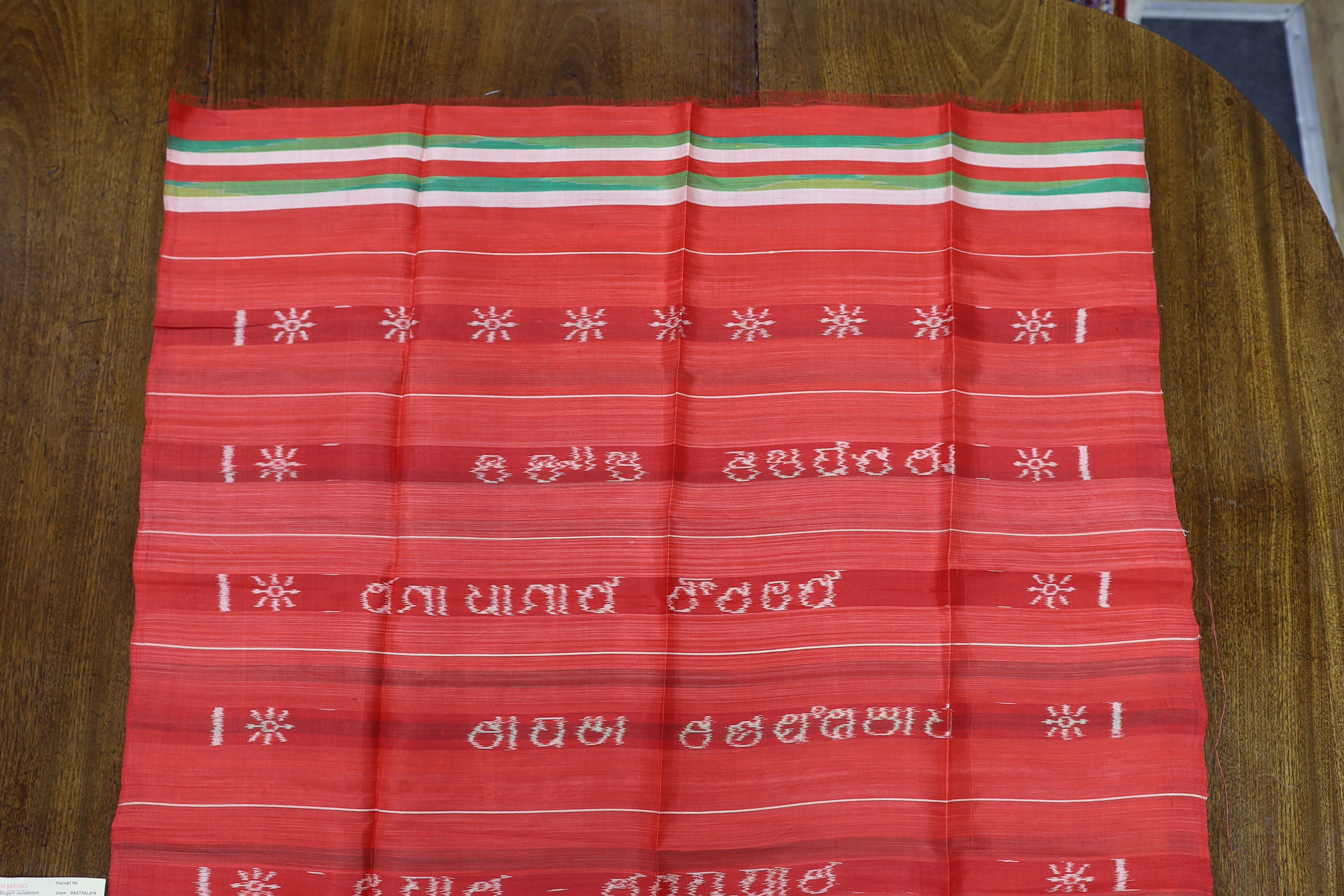 An Indian silk woven cloth, possibly a temple cloth, from Orissa, printed on the warp, with original receipt and paper bag